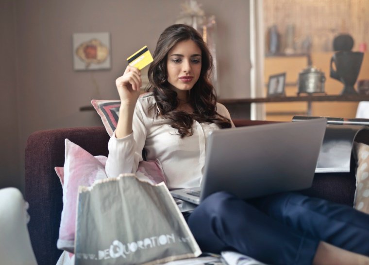 Bild von Frau mit Kreditkarte und Laptop auf Sofa Online Shopping nach Black Friday Angeboten