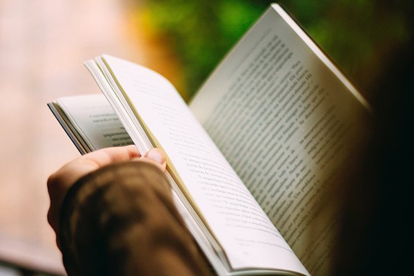 Personne en veste marron lisant in livre