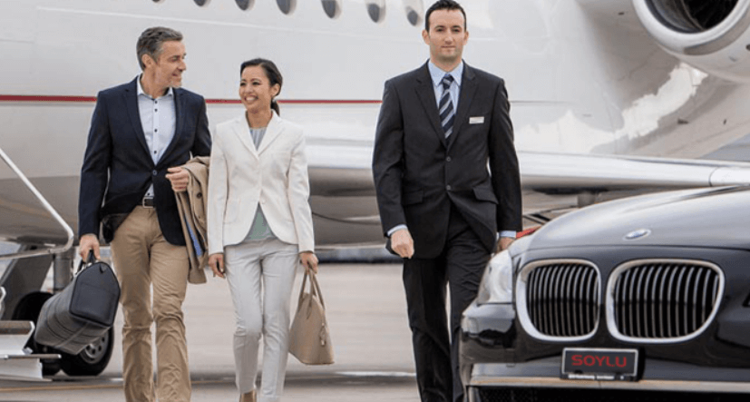 Airport Parking Manchester deals page banner - Image a man and woman being escourted from a plan to a waiting car by a suited man