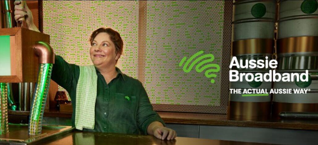 Aussie Broadband deals page image showing a woman in a coffee shop smiling with company logo to the side