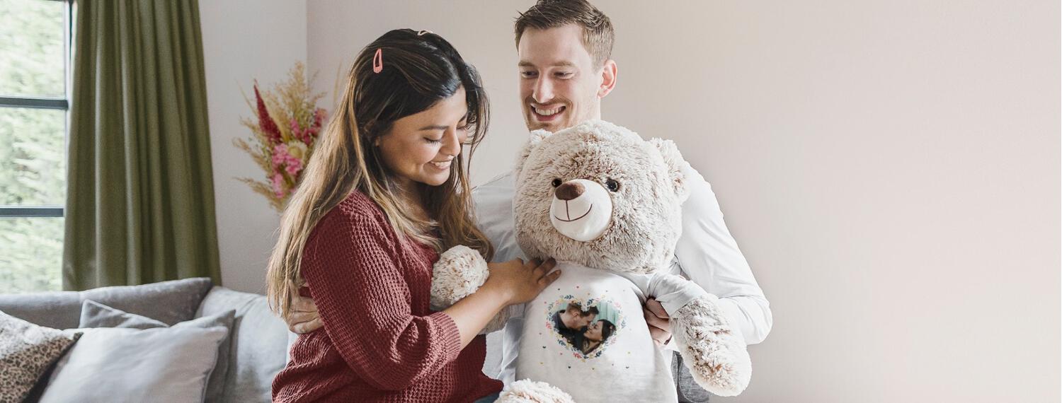 bannière photo Your Surprise montrant un couple souriant tenant une grosse peluche personnalisée
