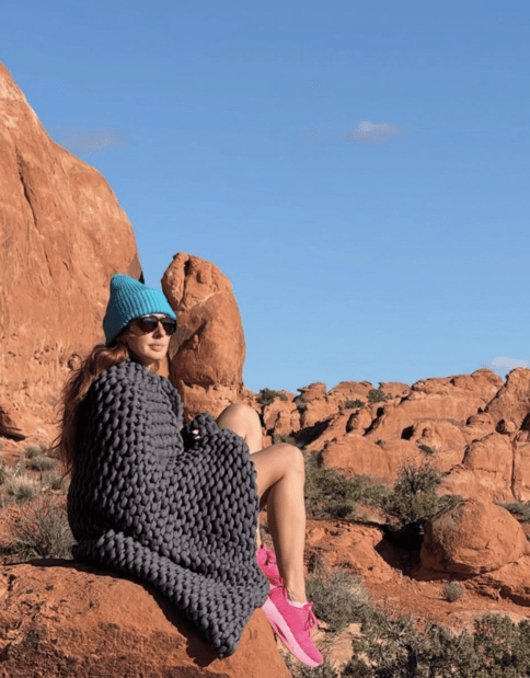 woman sitting on a canyon with a knitted blanket