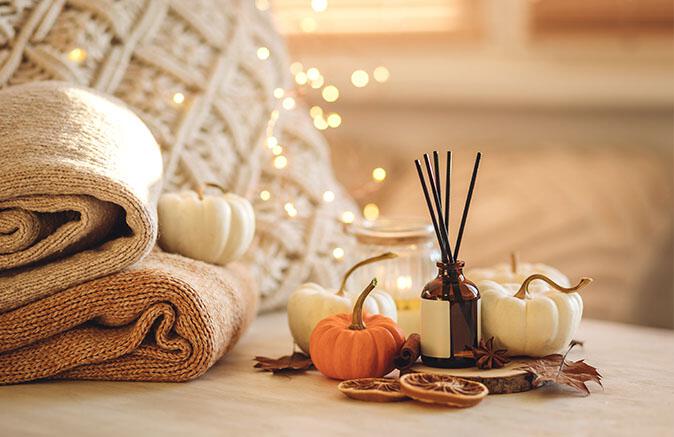 Blankets and pumpkins next to incense