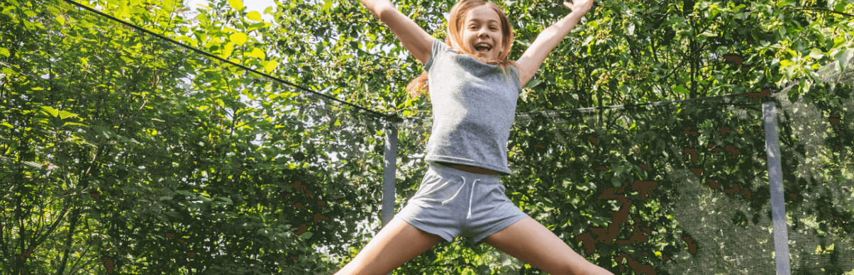Big Game Hunters Banner - Girl doing a starjump on a trampoline