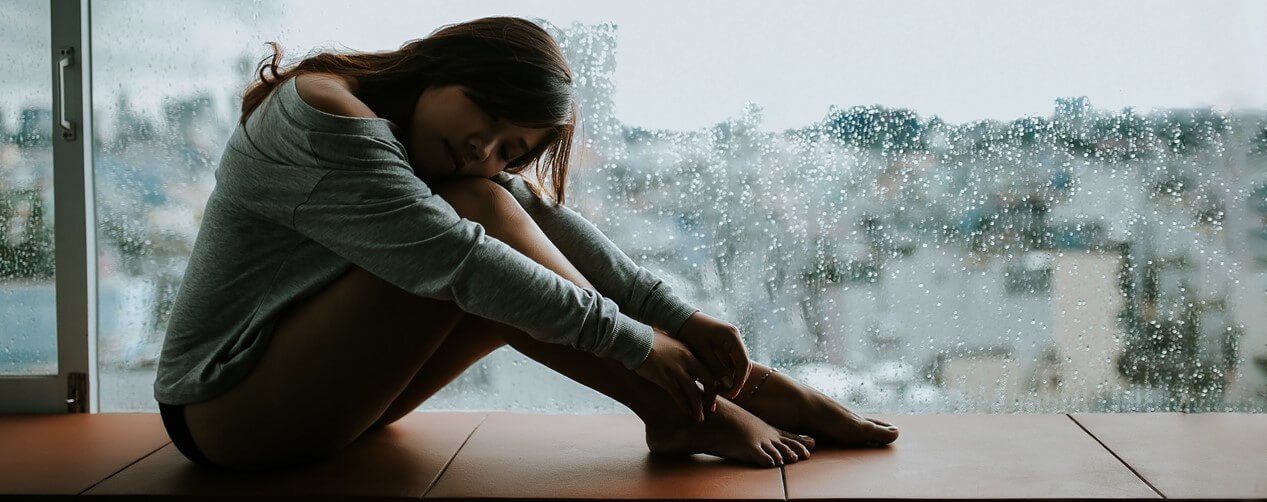 Blue monday sad woman in front of window