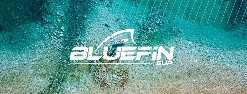 Ein Strand mit ozeanblauen Wasser, auf dem eine Person mit Bluefin SUP Board paddelt