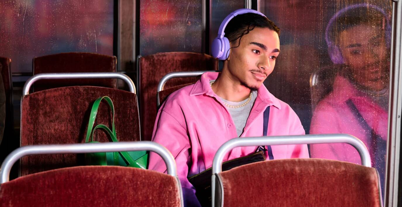 BookBeat savings tips banner featuring a man wearing a pink jacket and headphones, gazing out the window of a bus interior