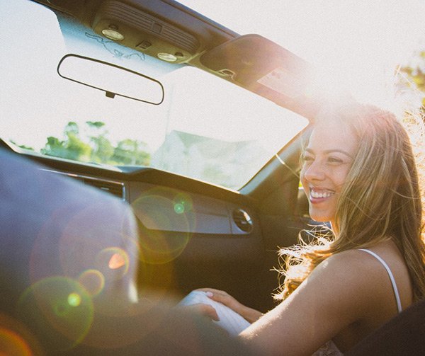 Femme qui sourie dans une voiture décapotable