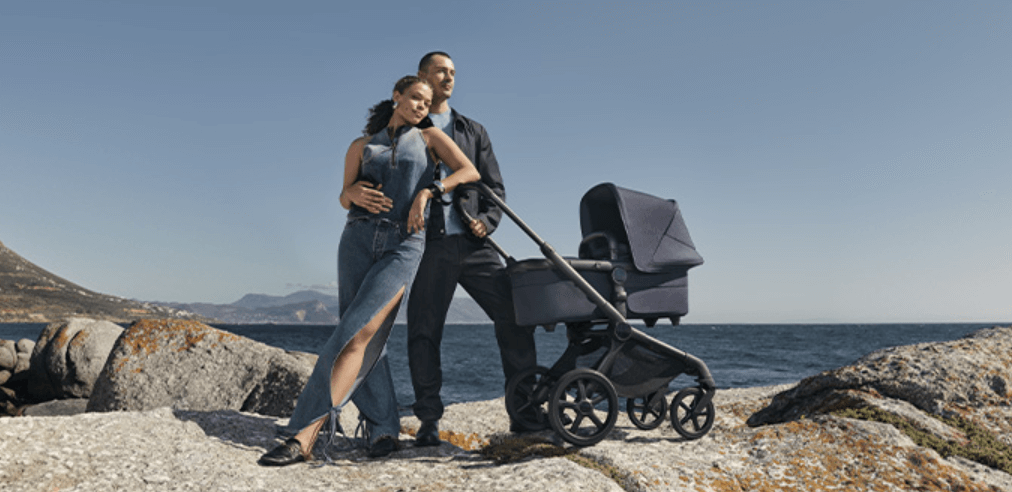 Bugaboo deals page banner showing a man and woman hugging beside a pram on some rocks by the coast