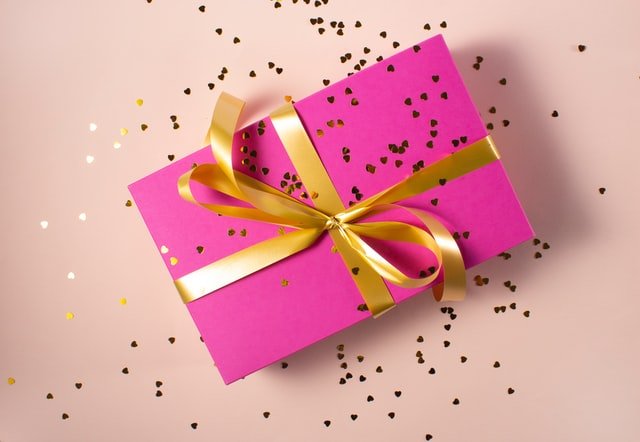 Cadeau rose avec ruban et confettis dorés