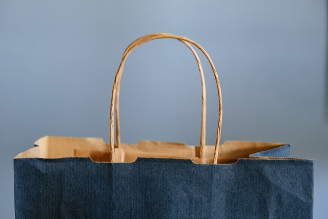 Sac en papier bleu marine devant un mur gris