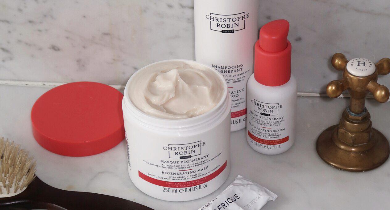 Christophe Robin savings image showing a selection of branded beauty products in white and red containers, beside a sink