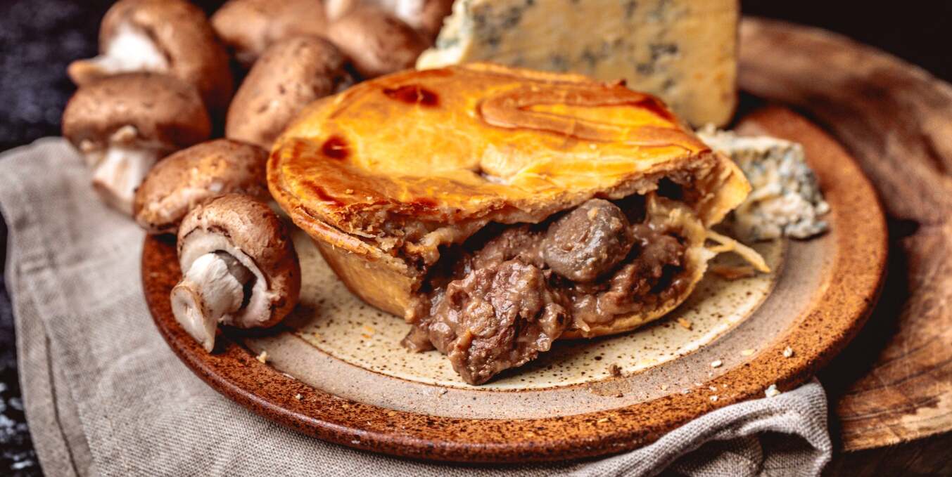 Chunk of Devon offers page - A deep-filled meat pie on a plate with mushrooms