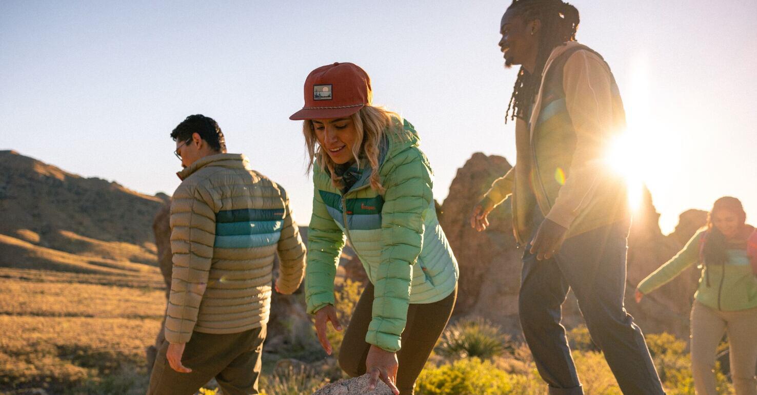 Cotopaxi Savings Guide - 4 people wearing branded jackets in a remote location blanketed by sunshine