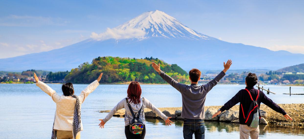 Crystal Travel savings page banner showing 4 people with their hands raised in front of mount Fuji