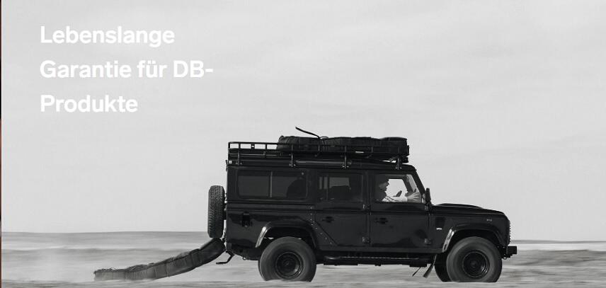 Geländewagen zieht Db Journey Gepäck auf hartem Grund hinter sich her; Hinweis auf die lebenslange Garantie bei Db Journey