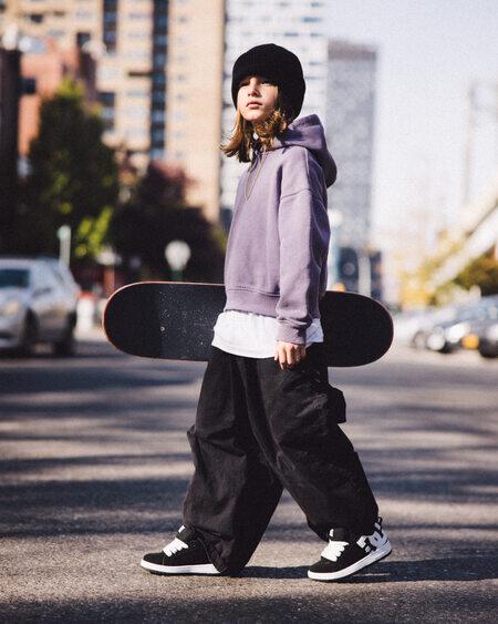kid holding skateboard wearing dc shoes