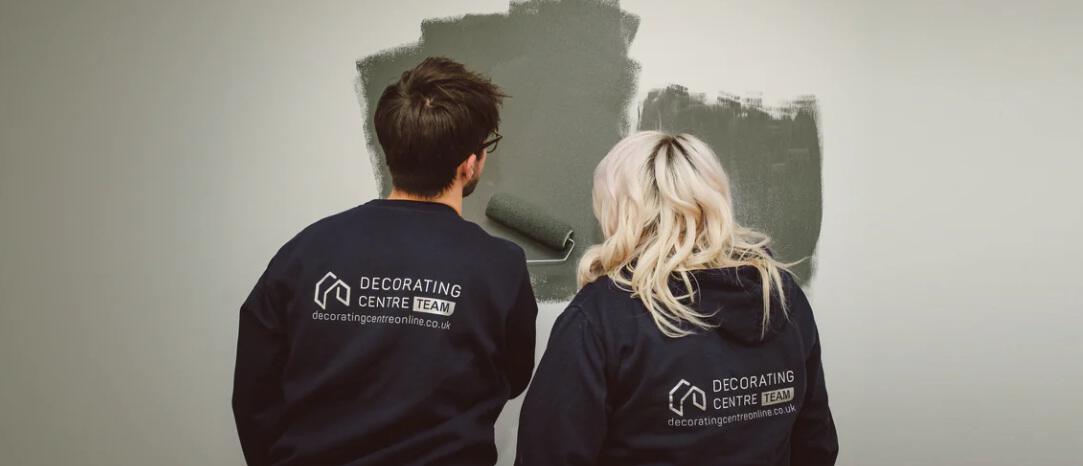 Decorating Centre Online offers banner featuring 2 people wearing sweatshirts with the company logo on the back painting a wall