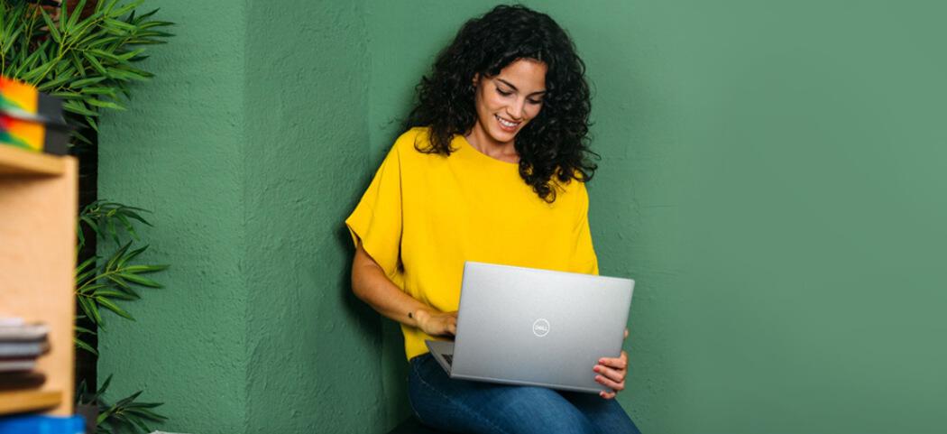 Dell Refurbished offers page banner featuring a woman in a yellow t-shirt holding an open laptop against a green background
