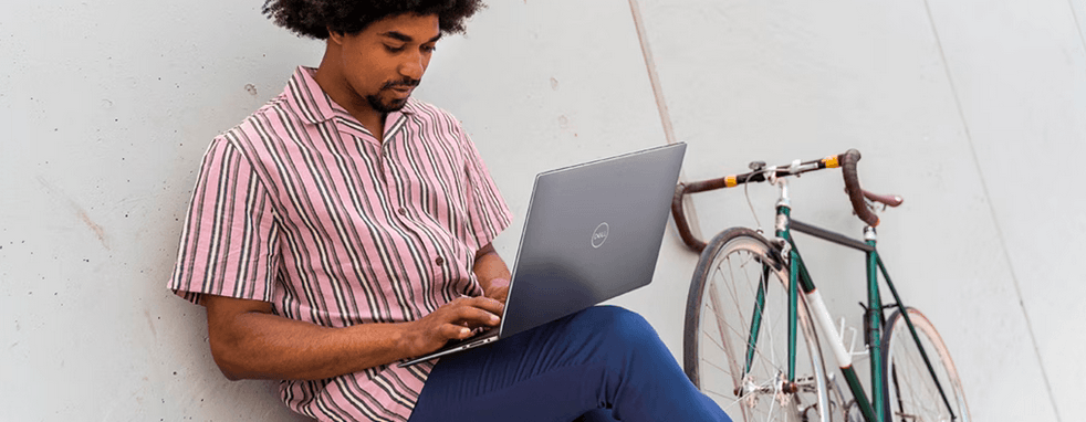 An Wand lehnender Mann arbeitet an Dell Laptop