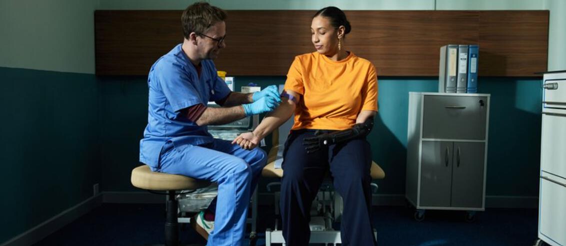 male nurse checking the bloods of a woman in a clinic setting