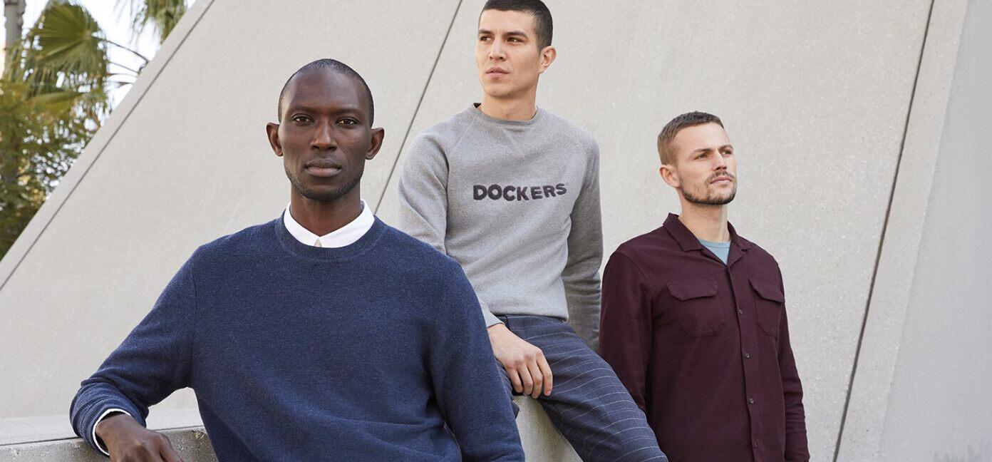Dockers ways to save banner - Three men wearing jumpers and shirts against a grey backdrop