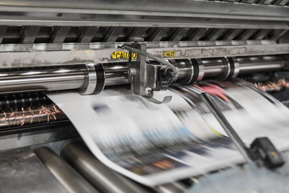 Banner für die Druckerpatronenexpress Gutscheinseite: bedrucktes Plakat kommt aus großer Druckmaschine