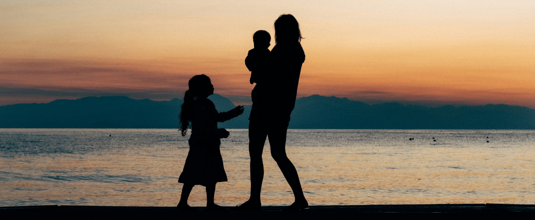 Easter single parent family holidays image showing a mum and two children silhouetted on a beach