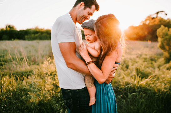 Vater Mutter und kleines Kind als Familie in einem Feld bei Sonnenuntergang