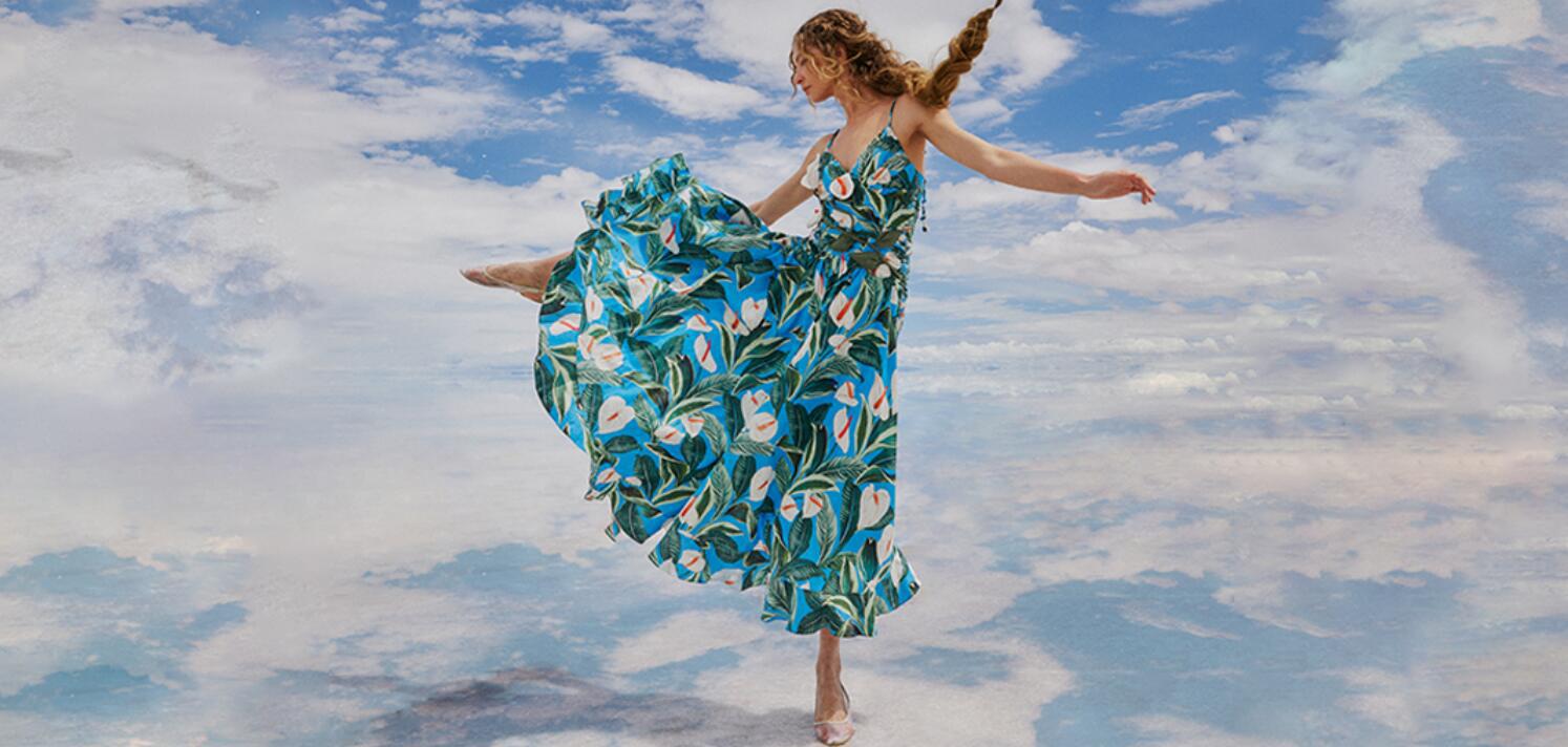 Farm Rio how to save money guide - Woman in a blue dress kicking her leg in front of a cloudy background
