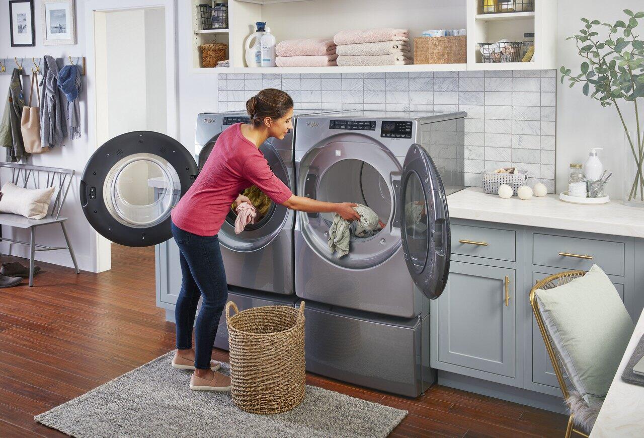 femme vue de dos faisant une lessive sur deux machines à laver