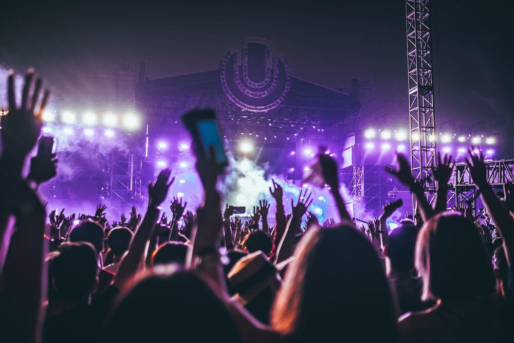 Foto einer Festivalmenge vor lila beleuchteter Bühne bei Nacht