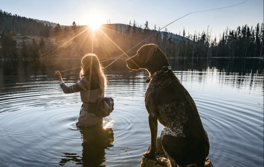 Woman and dog fishing in a lake with Orvis fishing tackle