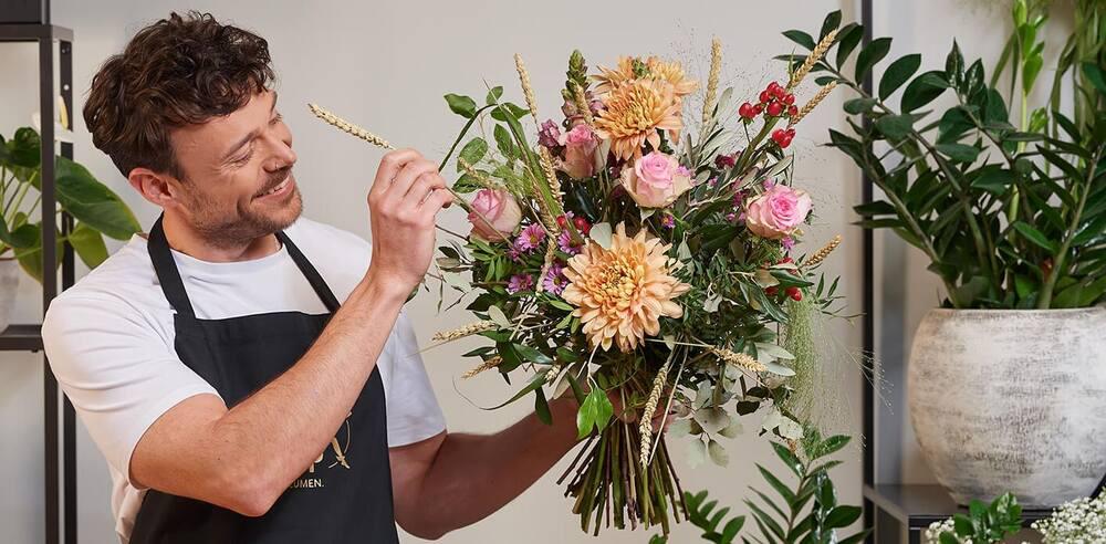 Banner für die Fleurop Gutscheinseite: Junger Florist vollendet einen Blumenstrauß