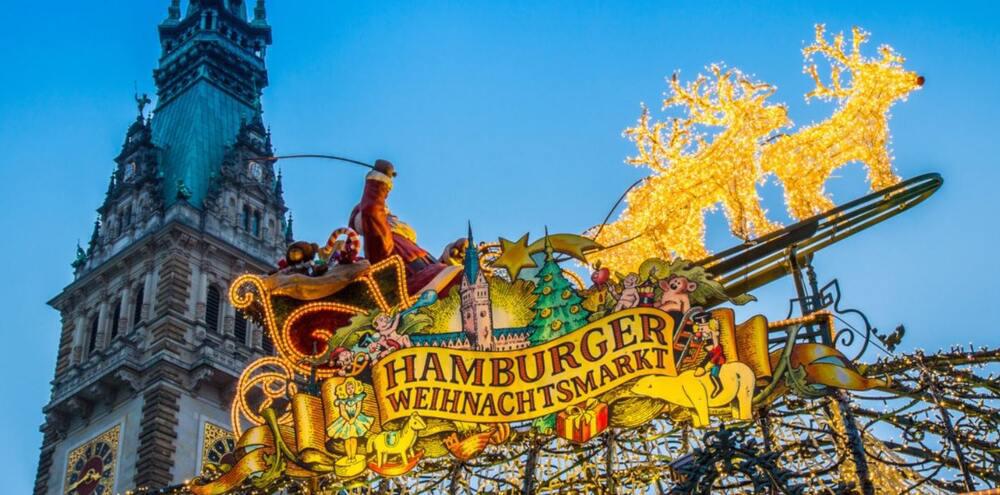 Leuchtendes Schild für den Hamburger Weihnachtsmarkt vor Rathausturm, den du mit Flixbus besuchen kannst