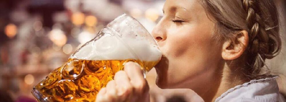 Frau trinkt eine Maß Bier als Banner für Flixbus Fahrten zum Oktoberfest