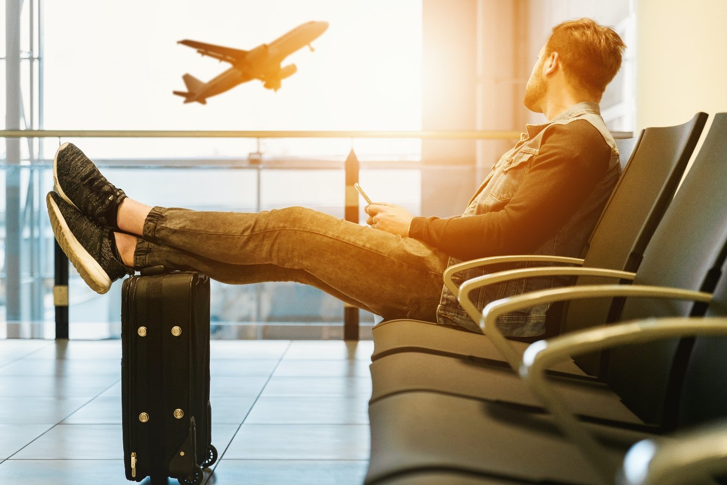 Mann am Flughafen Gate waehrend Flugzeug abhebt
