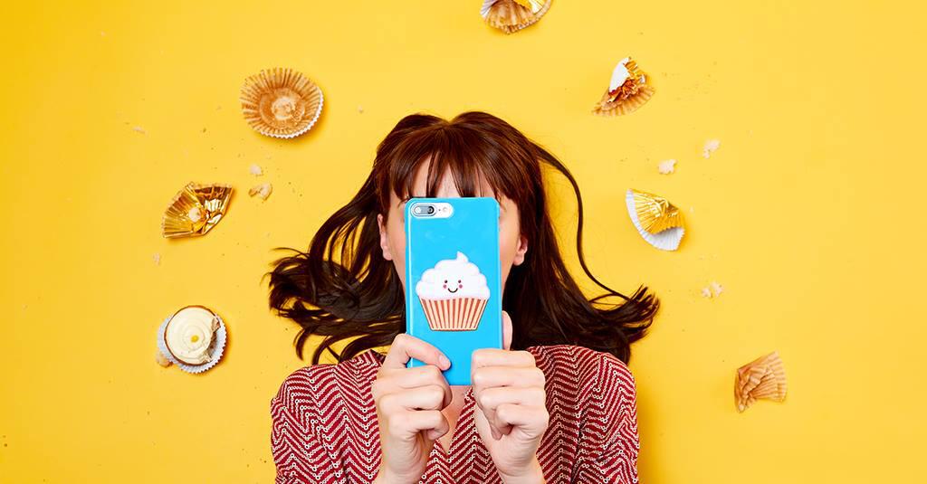 portrait photo RedBubble d'une femme tenant un téléphone bleu devant son visage sur fond jaune