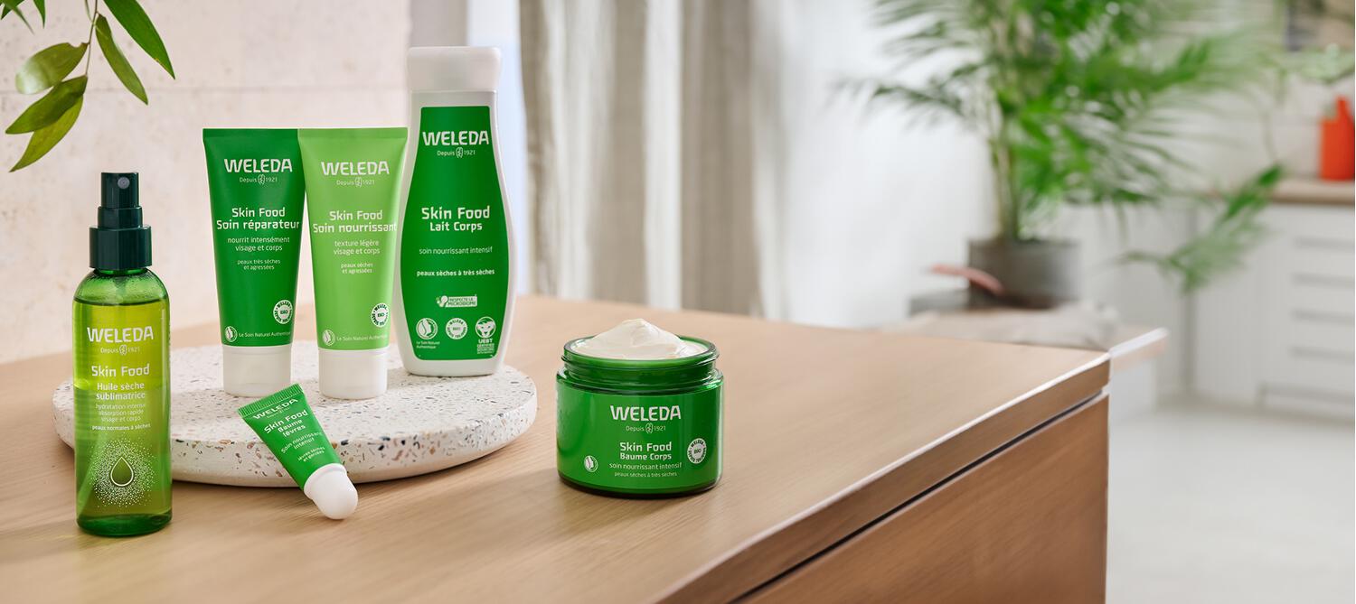 6 produits de la gamme Skin Food Weleda posée sur un meuble en bois