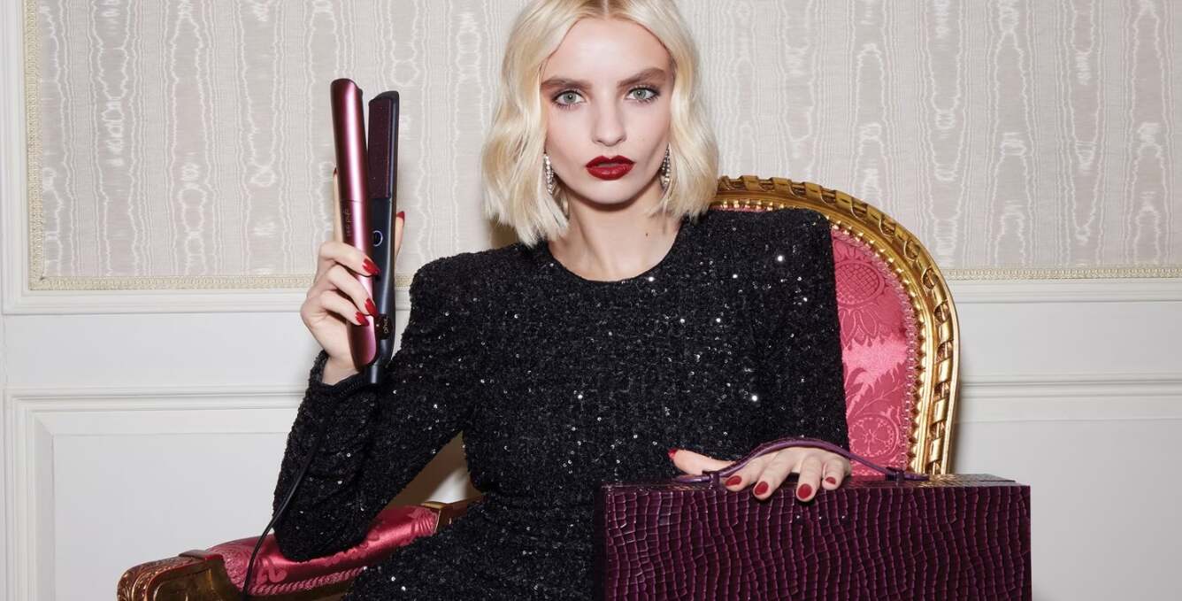 ghd deals page banner featuring a stylish woman sitting down holding up a pair of straighteners