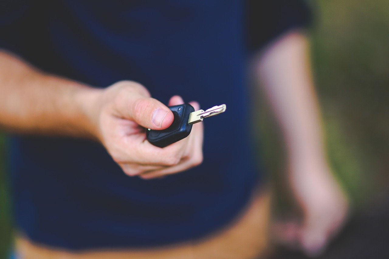 Homme en chemise bleue qui tient des clefs de voiture