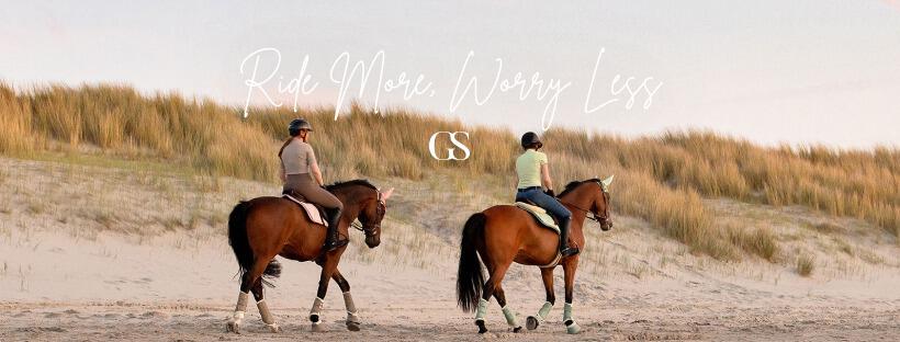 Two people riding horses on a beach in GS Equestrian horse riding clothing