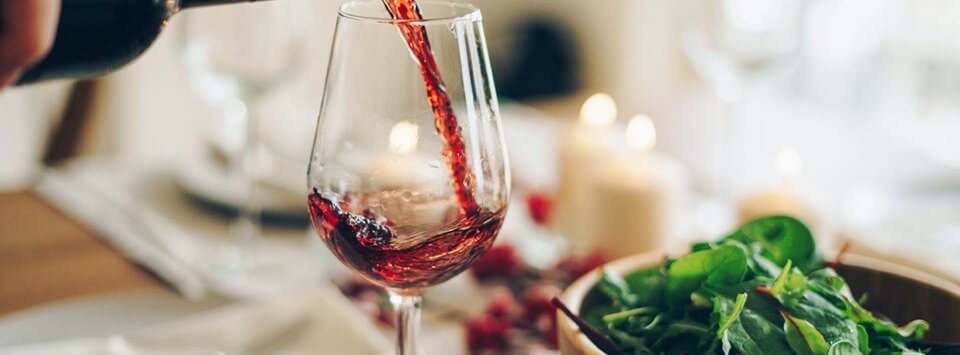 Banner für die Hawesko Gutscheinseite – Foto: Rotwein wird in ein Weinglas eingeschenkt
