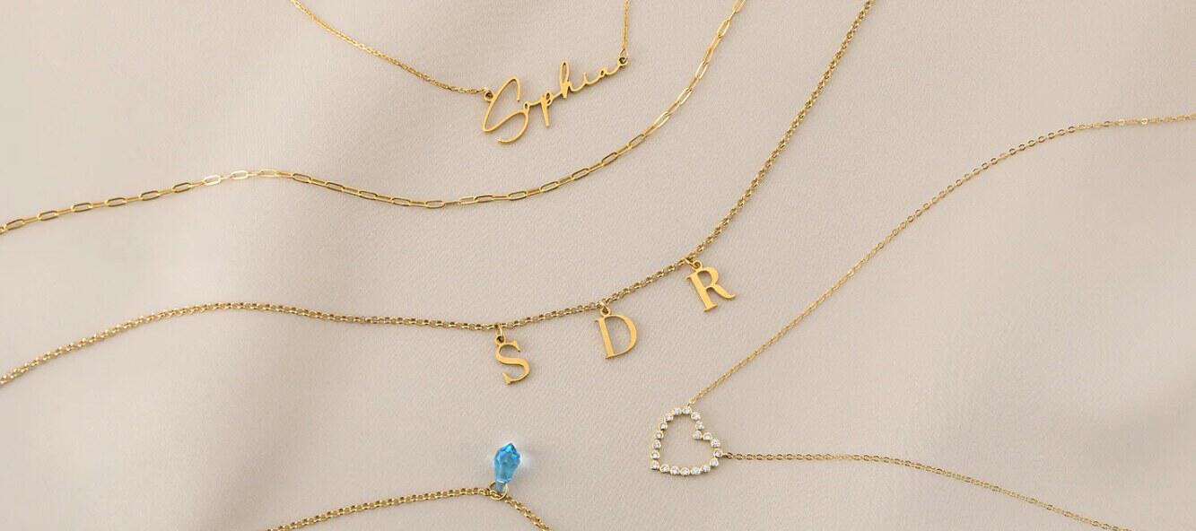 Hey Big Day savings guide image - A collection of gold chains. The jewellery feaures the name Sophie, the letters SDR and a heart