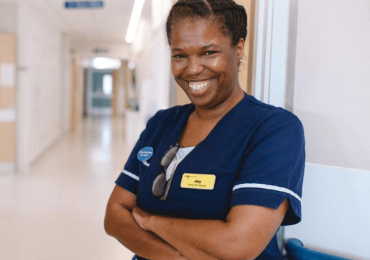 Hospice worker image showing a smiling woman in a blue care home uniform