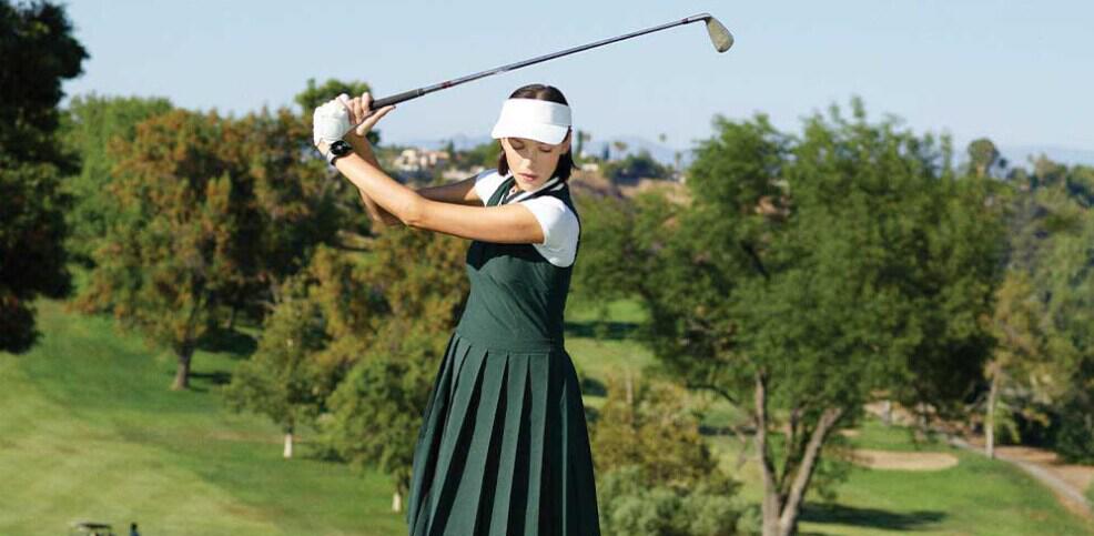 HOTGOLF discounts page image - A woman dressed in golf clothing raising a golf club ready to hit the ball on a course