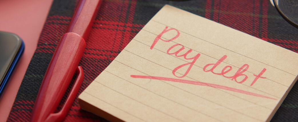 How to save quickly debt image picture showing a note with the text 'pay debt' written on it, a pen can be seen alongside