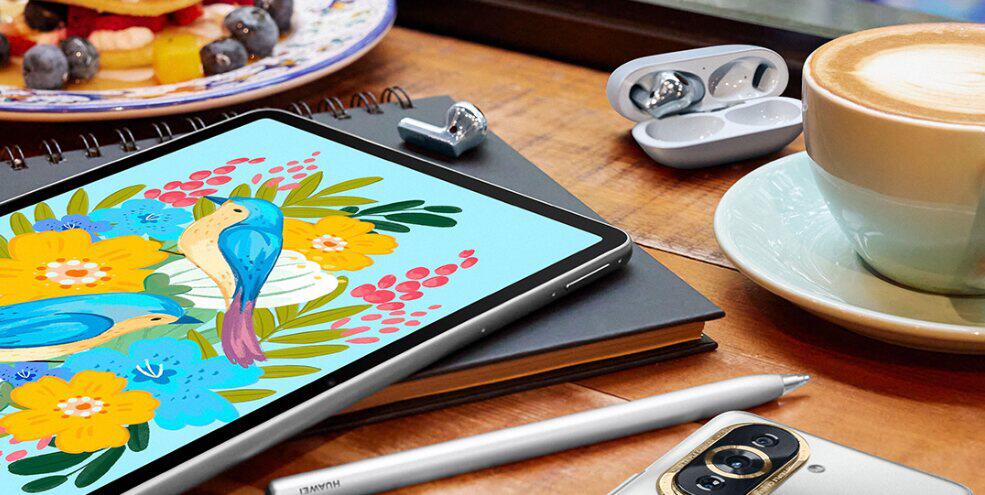 Huawei page banner showing assorted technology on a kitchen table, including a tablet and ear buds