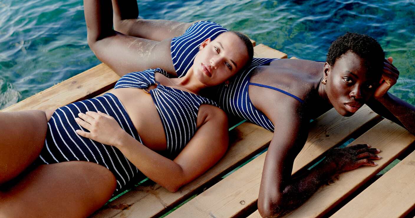 Hunza G how to save money guide - 2 woman wearing the same blue and white swimwear relaxing next to the sea