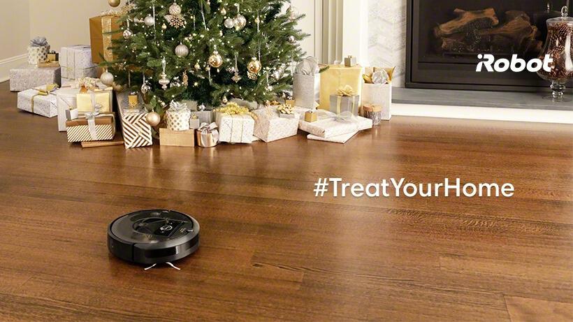 photo d'un aspirateur iRobot devant des cadeaux placés sous un sapin de Noël